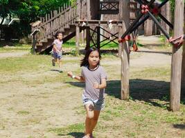 Kids play outdoors on a playground with modern slides, rope net bridges, climbing swings, climbers in summer. photo