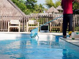 Cleaning pool, A man with cleaning equipment on hand for swimming pool. photo