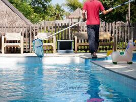 Cleaning pool, A man with cleaning equipment on hand for swimming pool. photo