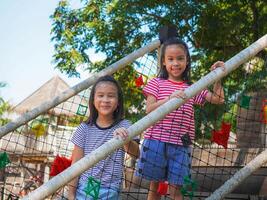 Kids play outdoors on a playground with modern slides, rope net bridges, climbing swings, climbers in summer. photo