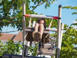 Kids play outdoors on a playground with modern slides, rope net bridges, climbing swings, climbers in summer. photo
