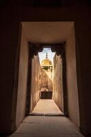 A doorway leading to a courtyard with a dome in the background photo
