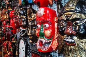 Many different types of masks are displayed on a wall photo