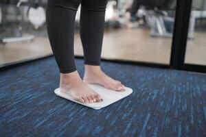 Fat diet and scale feet standing on electronic scales for weight control. Measurement instrument in kilogram for a diet control. photo