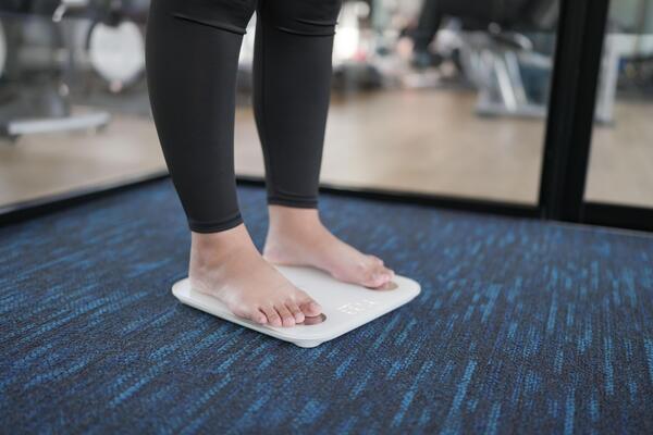 Fat diet and scale feet standing on electronic scales for weight control. Measurement instrument in kilogram for a diet control.