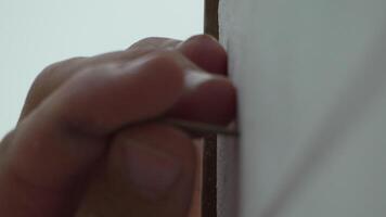 A man hands using a power tool fastens a board with a screw. Slow motion video