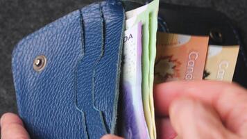 A closeup view of cash being stored in a blue wallet for financial purposes video