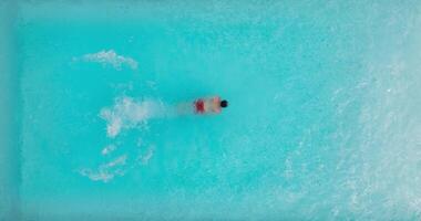 Aerial view as a man dives into the pool and swims. Slow motion video