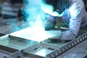 Close-up Welder doing water-cooled welding taking protective measures in factory. photo