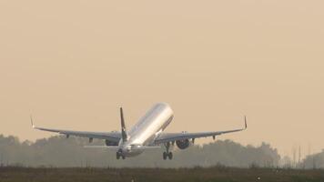 Footage of a commercial jet taking off. The airliner with an unrecognizable livery is backlit video