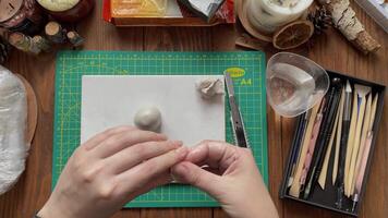 Woman make form of clay with wet hands. Tools for modeling and design of ceramic souvenirs. Hobbies, handmade and crafts. Stationery knife, cup with water and sticks on wooden table. video