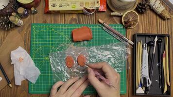 Women's hands draw face on clay with metallic stick. Tools for modeling and design of ceramic souvenirs on wooden table. Hobby, handmade and crafts. video