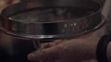 Close-up of lid of pan. Preparation dinner for family and guests. Woman is stirring dumplings with spoon in background. Home cooking. video