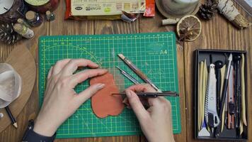 Person's hands cuts out oval from piece of clay with knife. Tools for modeling and design of ceramic souvenirs. Hobbies, handmade and crafts. video