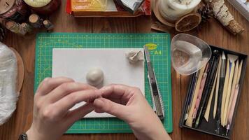 Master make form of clay with wet hands. Tools for modeling and design of ceramic souvenirs. Stationery knife, cup with water and sticks on wooden table. Hobbies, handmade and crafts. video
