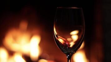 Flames in an empty glass on the background of fire in the fireplace video