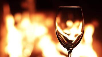 Flames in an empty glass on the background of fire in the fireplace video
