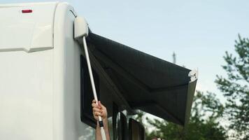 A man folds the awning of a motorhome in a summer camping. Closing the awning in a mobile home video