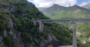 Drone flyby of a railway bridge in Corsicas dramatic mountains highlighting rugged landscape views video
