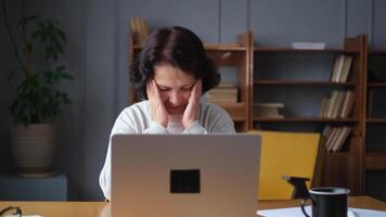 Middle aged senior woman at home relaxing stretching hands and body taking break from work on laptop. Older mature woman happy after work done satisfied by good result. Fatigue from long laptop usage video