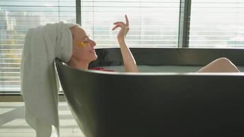 Spa relaxation. Woman lying in bath with red roses petals. Girl relaxing in bathroom at home. Pretty female enjoying taking hot bath. Stress relief. Rest after hard working day video