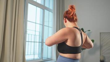 Fitness workout training. Woman practicing fitness at home. Plus size female doing sports exercise at home indoor. Girl in sportswear have workout weight training for weight loss. Sport and fitness video