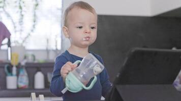 Toddler drinking from training cup while watching tablet video