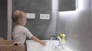 Toddler engaging in handwashing routine at a modern bathroom sink video