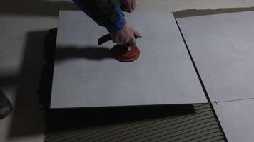 Tiler worker placing or tiling gray ceramic tile in the position over adhesive glue with lash tile leveling system, renovation or recontruction, concept of building video