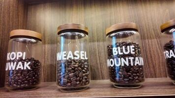 Roasted coffee beans in glass jars on shelves in coffee shops. Various specialty coffees, each with unique production methods, distinct flavors, and diverse origins. cafe in Hanoi, Vietnam. 4k footage video