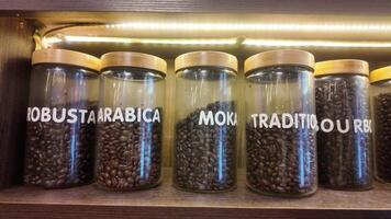 Roasted coffee beans in glass jars on shelves in coffee shops. Various specialty coffees, each with unique production methods, distinct flavors, and diverse origins. cafe in Hanoi, Vietnam. 4k footage video