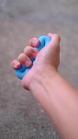 A close-up view of a hand gripping a blue silicone ring, ideal for hand strength training, stress relief, and muscle toning. video