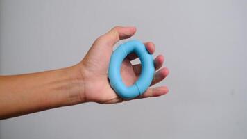 A close-up view of a hand gripping a blue silicone ring, ideal for hand strength training, stress relief, and muscle toning. video