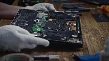 The person is holding a circuit component, specifically a motherboard, on a wooden table. video