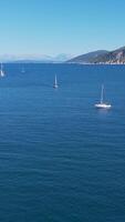 Sailboats in the open ocean near a mountain range video