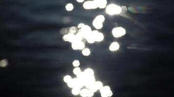 Defocused shot of a wavy water surface with a beautiful bokeh of sun glares which are reflected from the lake video