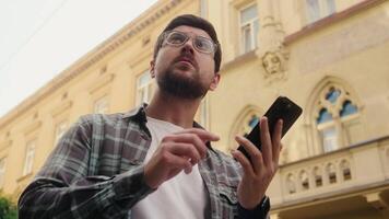 Caucasian man hold smartphone searching address location city lost confused looking around male guy tourist travel using mobile phone gps online map search direction guide need help navigator tourism video