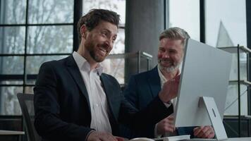 Happy smiling laughing caucasian men businessmen colleagues business partners looking computer screen reading email receive good news watching funny on internet office break successful teamwork video
