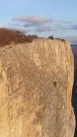 Top view of rocky cliff on background horizon of mountains. Shot. Beautiful landscape with majestic rocky cliff in hilly area. Rocks, cliffs, hills and lowlands in one terrain video