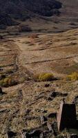 Old cemetery with ruins of ancient tombs located in mountains. Footage. Aerial view of the ancient burial place with brick wrecks on the background of mountain slope covered by trees. video