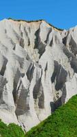 Amazing white mountains with green grass. Clip. Beautiful patterns on rocky white mountain with bright greenery on sunny summer day. White rocks of volcanic origin on island on summer day video