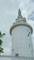 Low angle view of a white beautiful tower on blue cloudy sky background. Action. Concept of culture and architecture. video