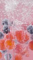 Berries fall into water on isolated background. Action. Juicy berries fall into water with bubbles. Refreshing fall of berries in water on light background video