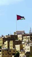 Enjoy the stunning panoramic view of Amman with the iconic Jordanian flag on display. Action video