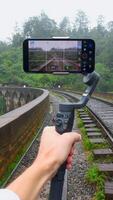 Shooting of trip on tripod phone. Action. Blogger professionally shoots videos on phone while traveling. Beautiful shooting on your phone in tropical jungle