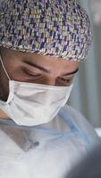 Close up of two male surgeons looking down at work. Action. Men doctors in wearing sterile masks and uniform during the procedure, concept of medicine. video