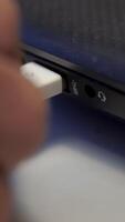 Hand inserting white USB cable into laptop isolated on white background. Media. Close up of connecting device to a computer with a cable. video