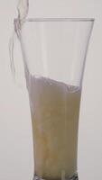 A hand of a drunk man pouring beer inside a long transparent glass and spilling it on the table. Action. Close up of beer alcoholic drink with a lot of foam on white background. video