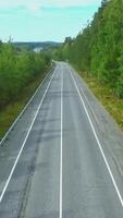 Flying over Scandinavian fir forest, crossing a country road. Footage. Aerial view of the empty road and summer forest. video
