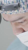 Close-up of surgeon performing operation. Action. Attentive and focused gaze of surgeon during operation. Professional surgeon with binoculars performs operation video